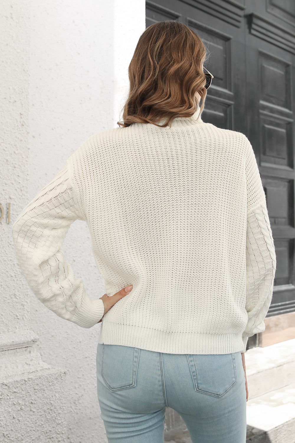 White cable knit turtleneck sweater with chevron detail on sleeves.