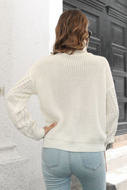 White cable knit turtleneck sweater with chevron detail on sleeves.