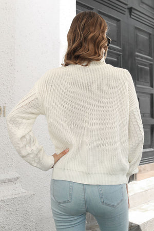 White cable knit turtleneck sweater with chevron detail on sleeves.