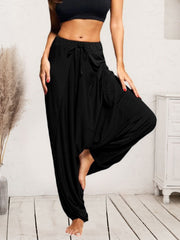 Black drape-front drawstring harem pants with a relaxed fit and wide legs.
