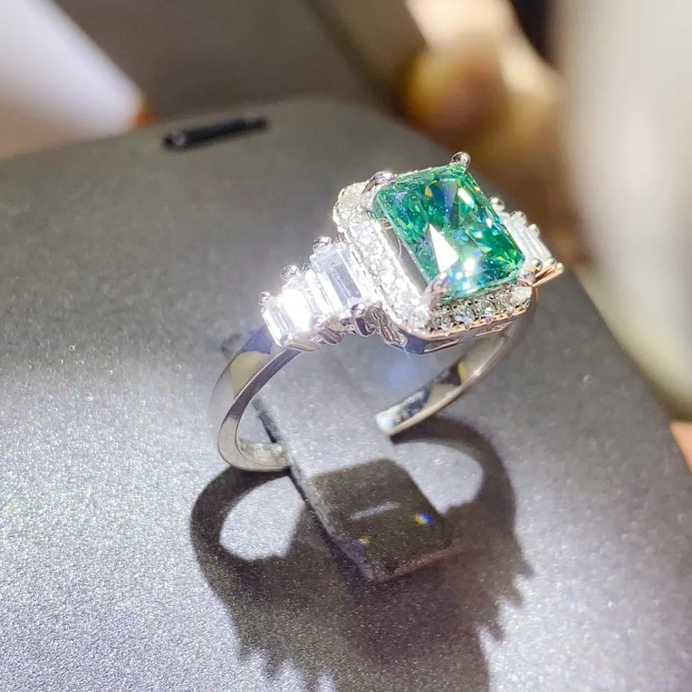 Silver emerald-cut moissanite halo ring with baguette and round accent stones.