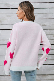 Light pink crewneck sweater with hot pink heart appliqués on sleeves.