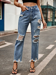 Medium wash denim jeans with ripped knees and raw hem straight leg cut.
