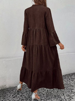 Brown tiered ruffle hem dress with bell sleeves and a button front, styled with white heels.