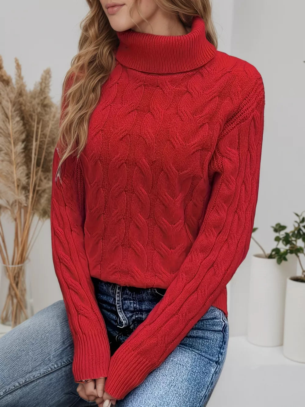Red cable-knit turtleneck sweater with a cozy, textured pattern.