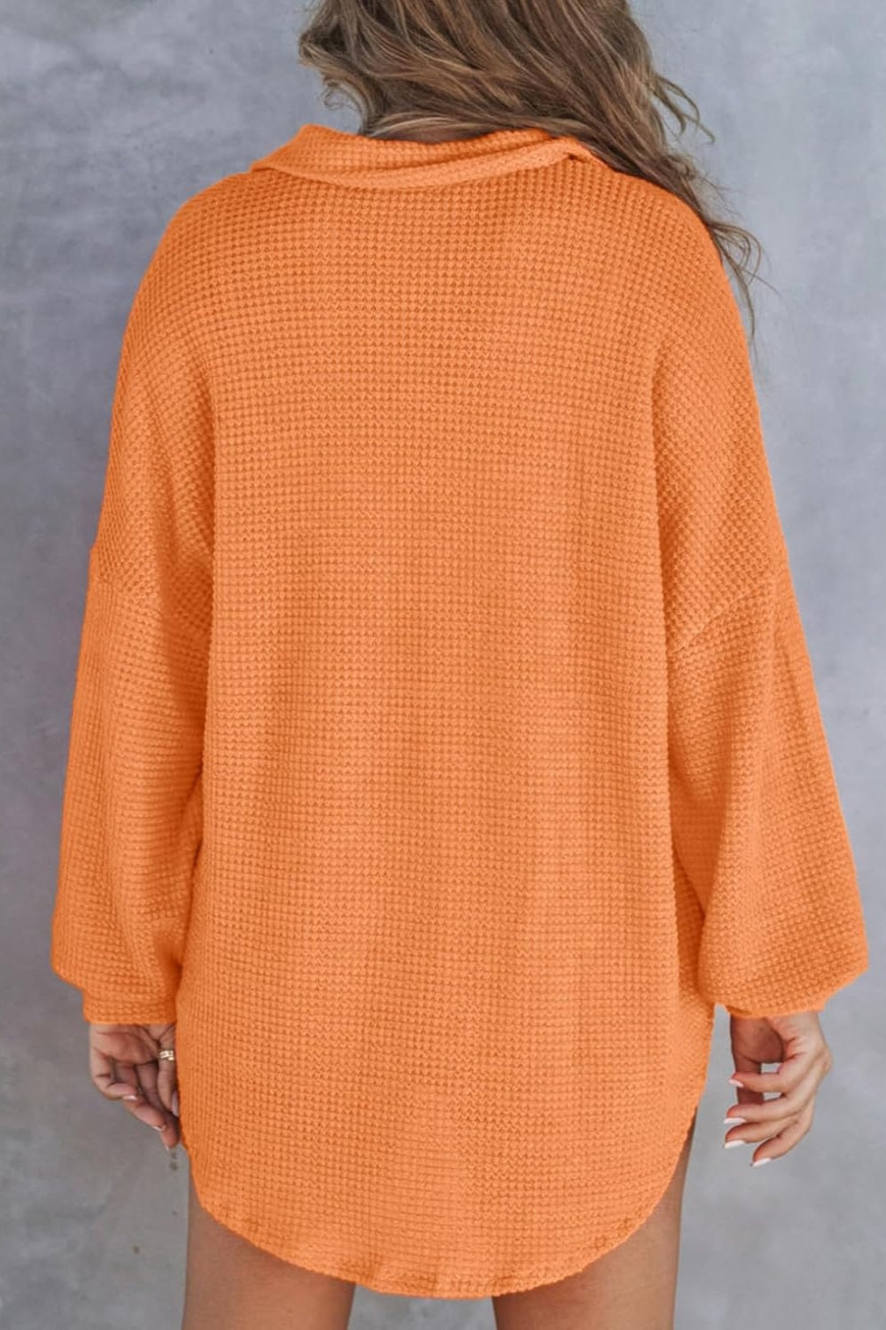 Orange waffle knit henley shirt with collar and long sleeves.