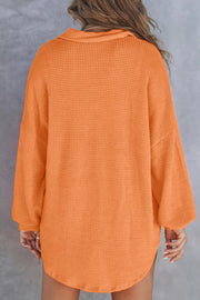 Orange waffle knit henley shirt with collar and long sleeves.