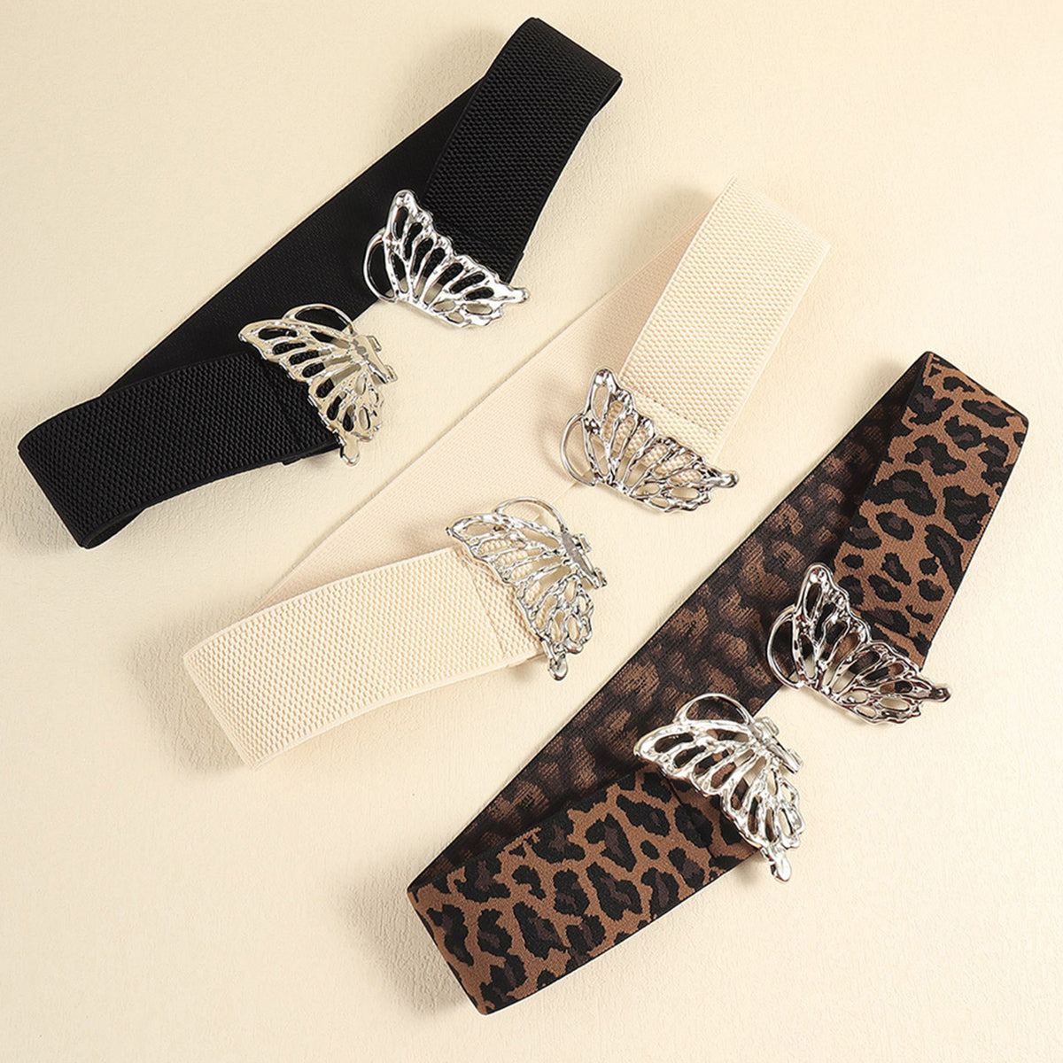 Elastic waist belts in black, light yellow, and leopard print with butterfly buckles