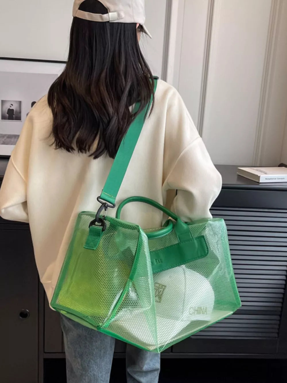 Green transparent PVC travel bag with mesh detailing and leather handles.