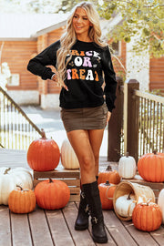 Black crewneck sweatshirt with "Trick or Treat" graphic in retro font and candy motifs.