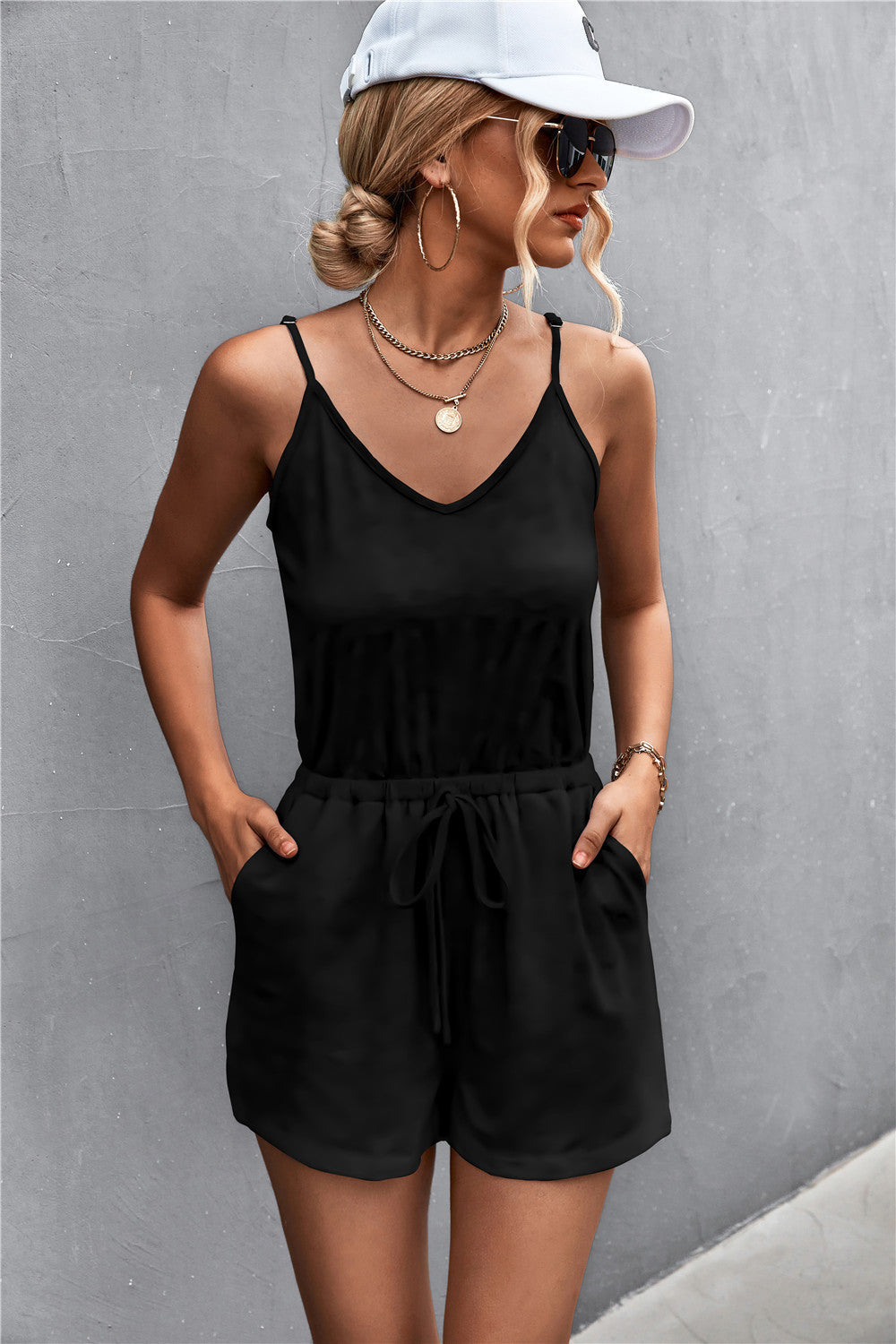 Black V-neck drawstring romper with adjustable spaghetti straps and pockets.