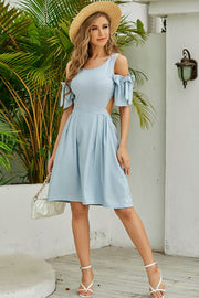 Light blue fit-and-flare dress with open back and bow sleeves.