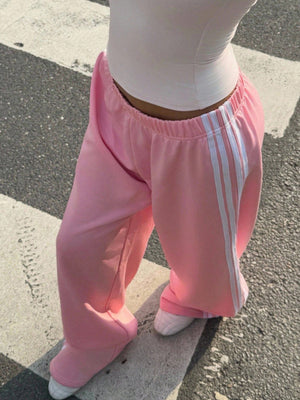 Pink relaxed wide leg sweatpants with white side stripes and elasticated waist.