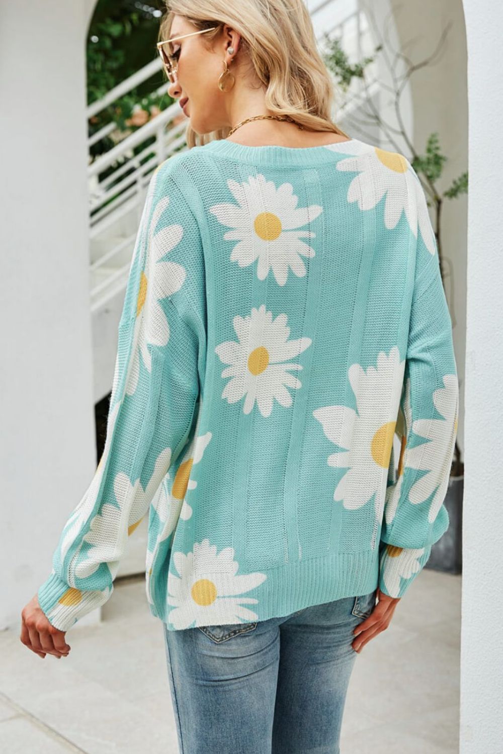 Light blue intarsia knit sweater with white daisy pattern, crew neck, long sleeves.
