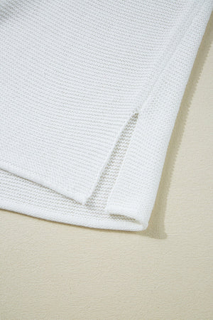 White knit crop top with side slits, acrylic material.