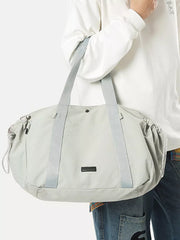 Light gray athletic nylon tote bag with racket holder and cinch cord closure.