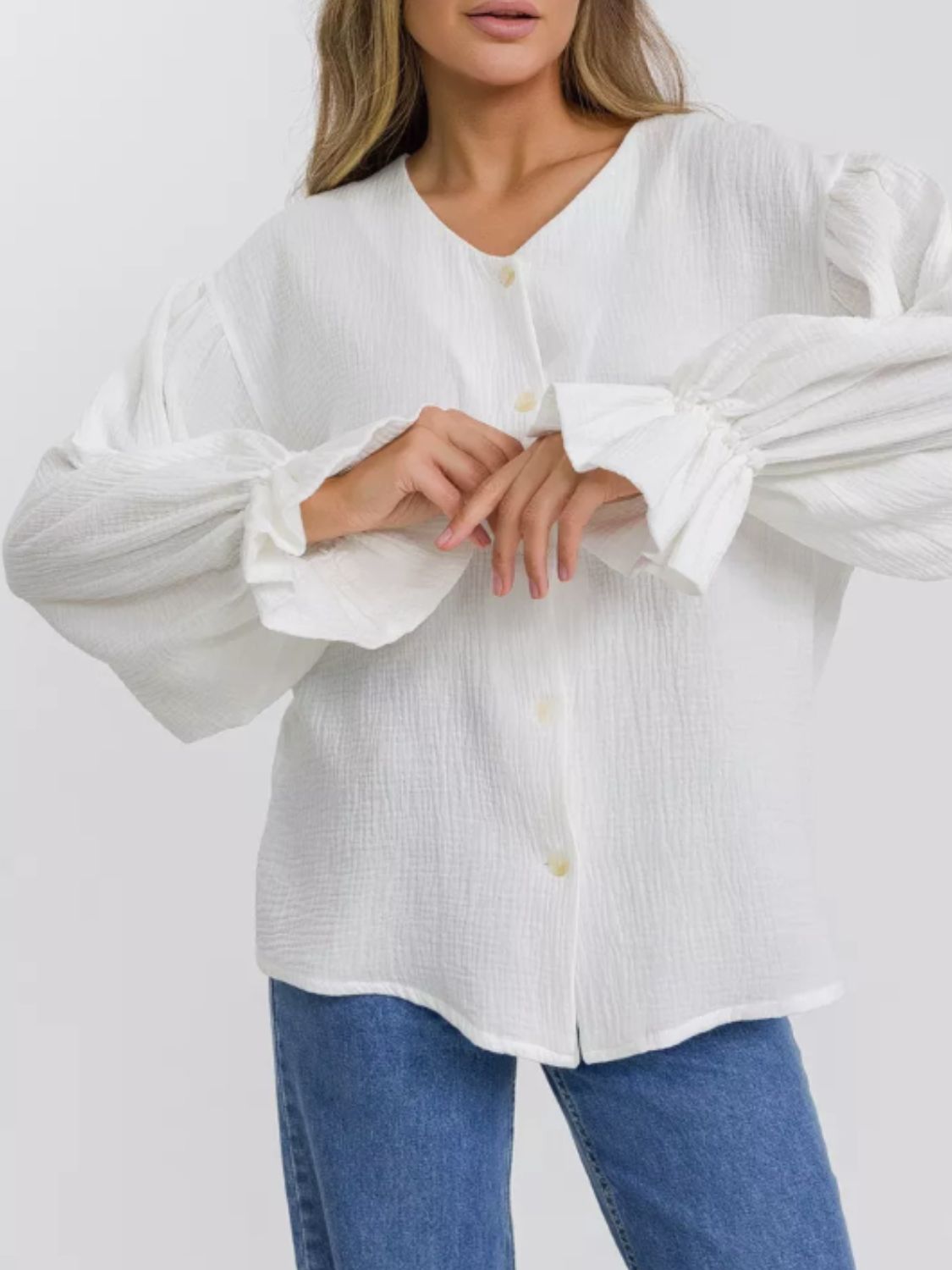 White textured puff sleeve blouse with ruffled cuffs and V-neck.