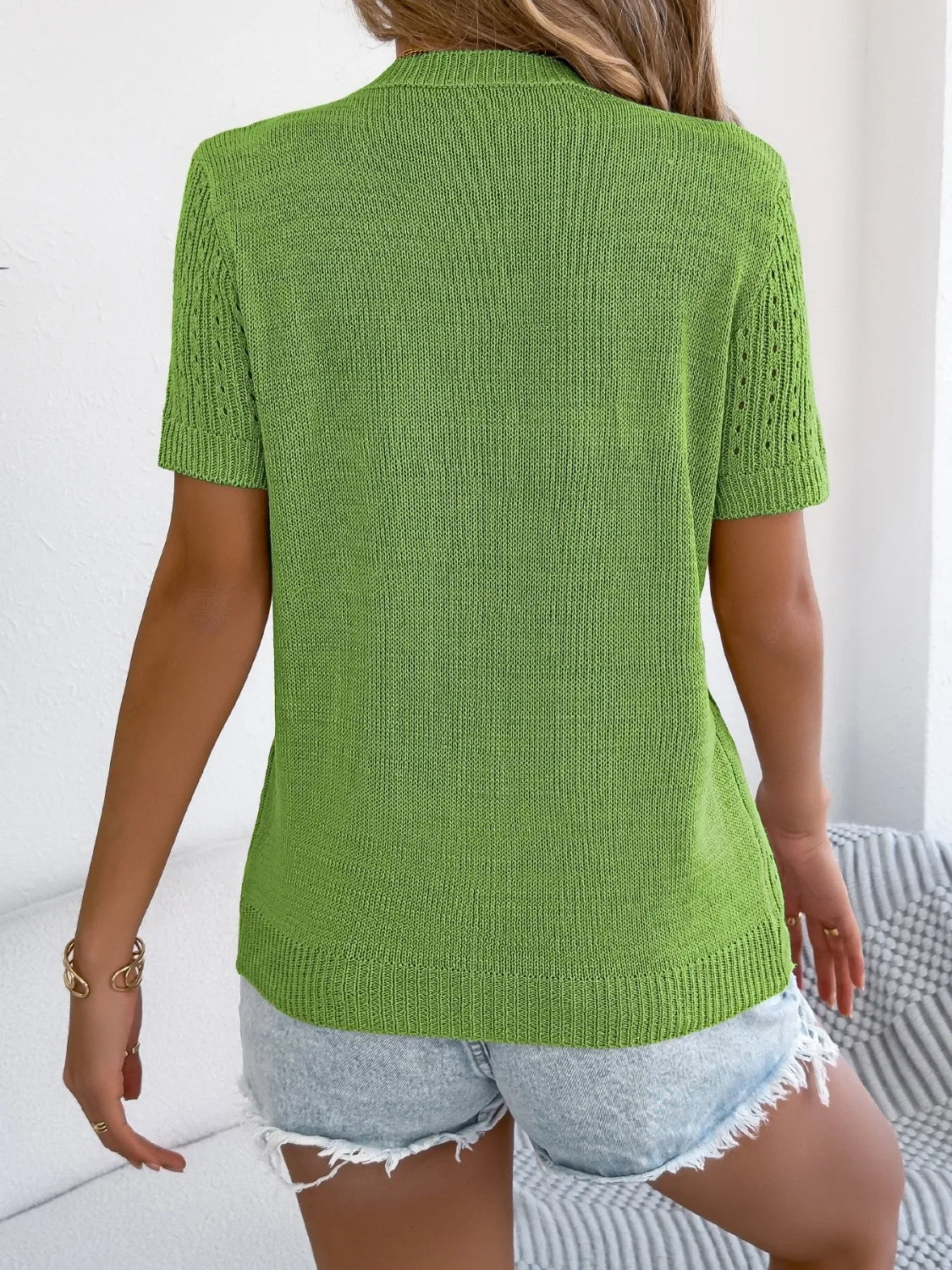 Green knit button-up cardigan with short sleeves and open knit detail on sleeves