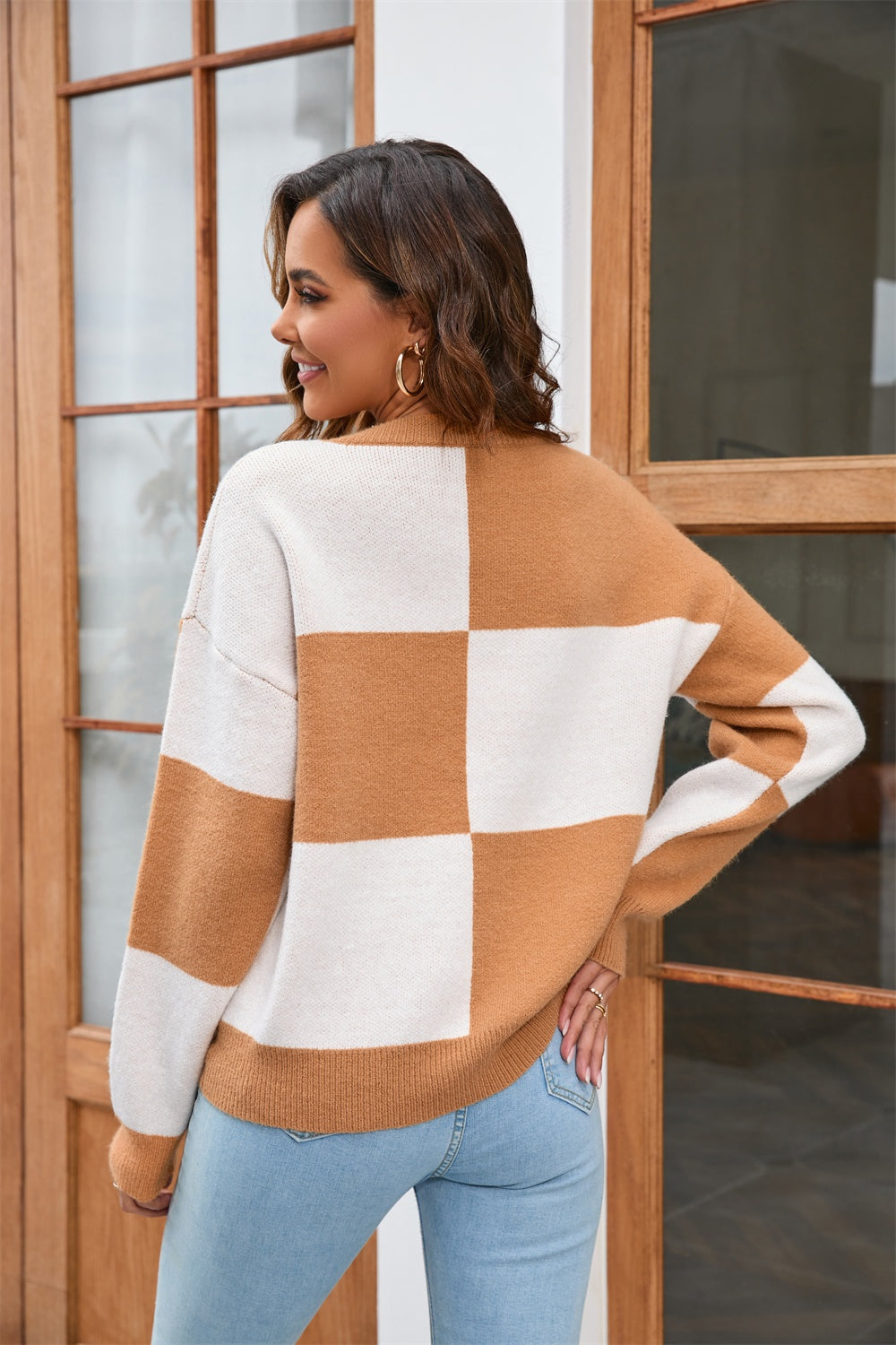 Checkerboard knit crewneck sweater in tan and white acrylic with long sleeves.