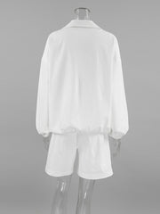 White two-piece set with collared long sleeve top and drawstring shorts, featuring snap details.
