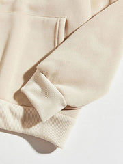 Cream hoodie with ribbed cuffs and hem, featuring a front pocket detail.