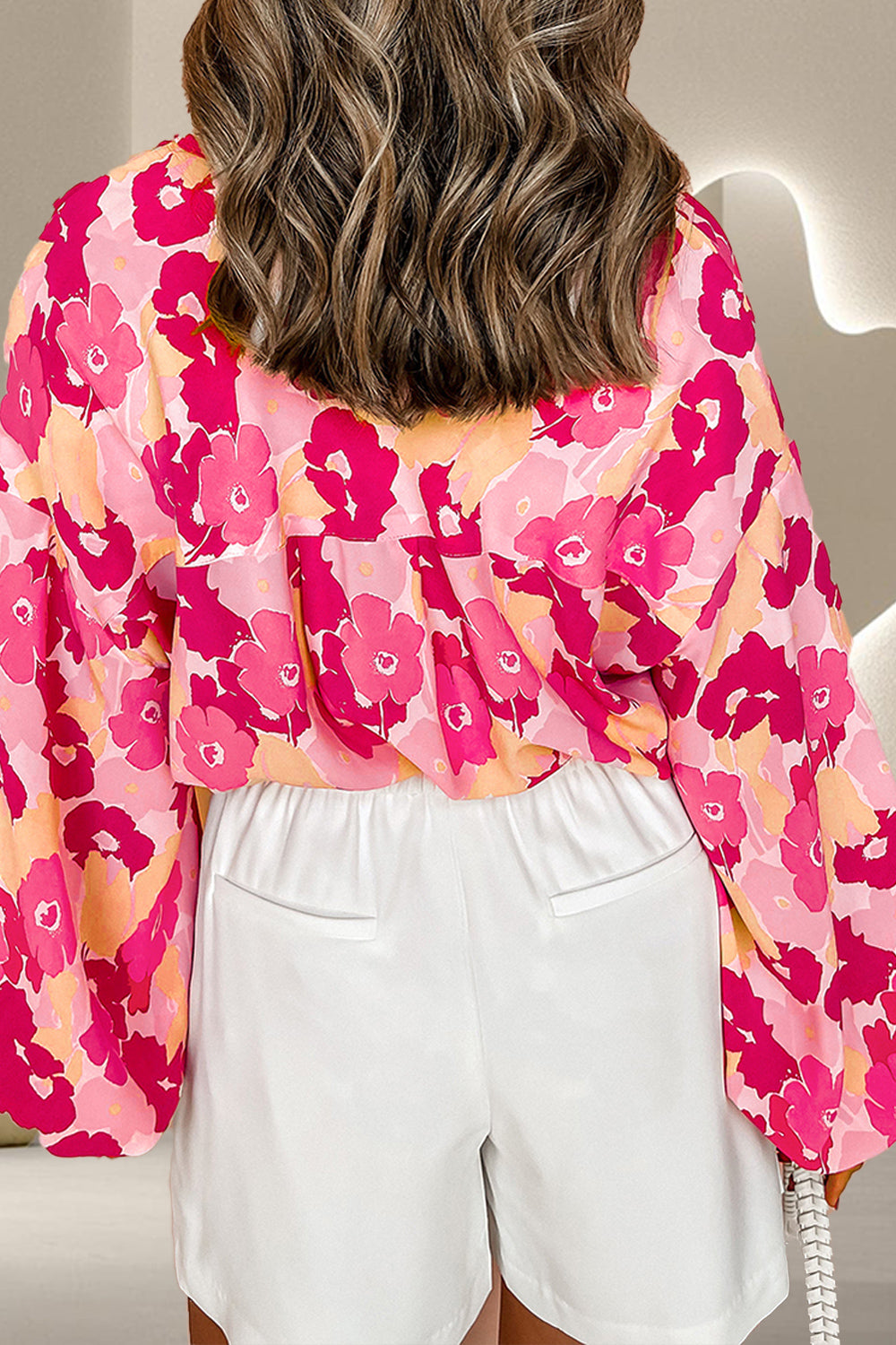 Floral print blouse in strawberry pink with balloon sleeves and a button front, styled with white shorts.