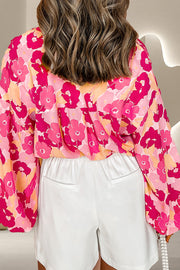 Floral print blouse in strawberry pink with balloon sleeves and a button front, styled with white shorts.