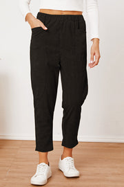 Black corduroy barrel-leg utility pants with elastic waist and pockets.