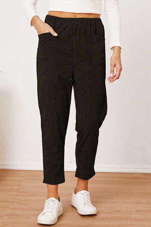Black corduroy barrel-leg utility pants with elastic waist and pockets.