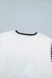 White ribbed sweater vest with black contrast trim neckline and armholes.