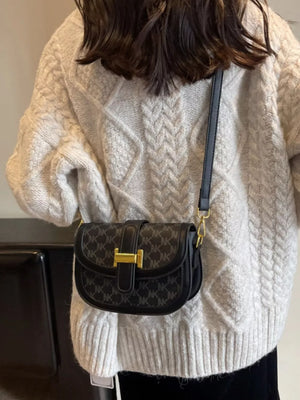 Black monogram flap crossbody bag with gold hardware and adjustable strap.