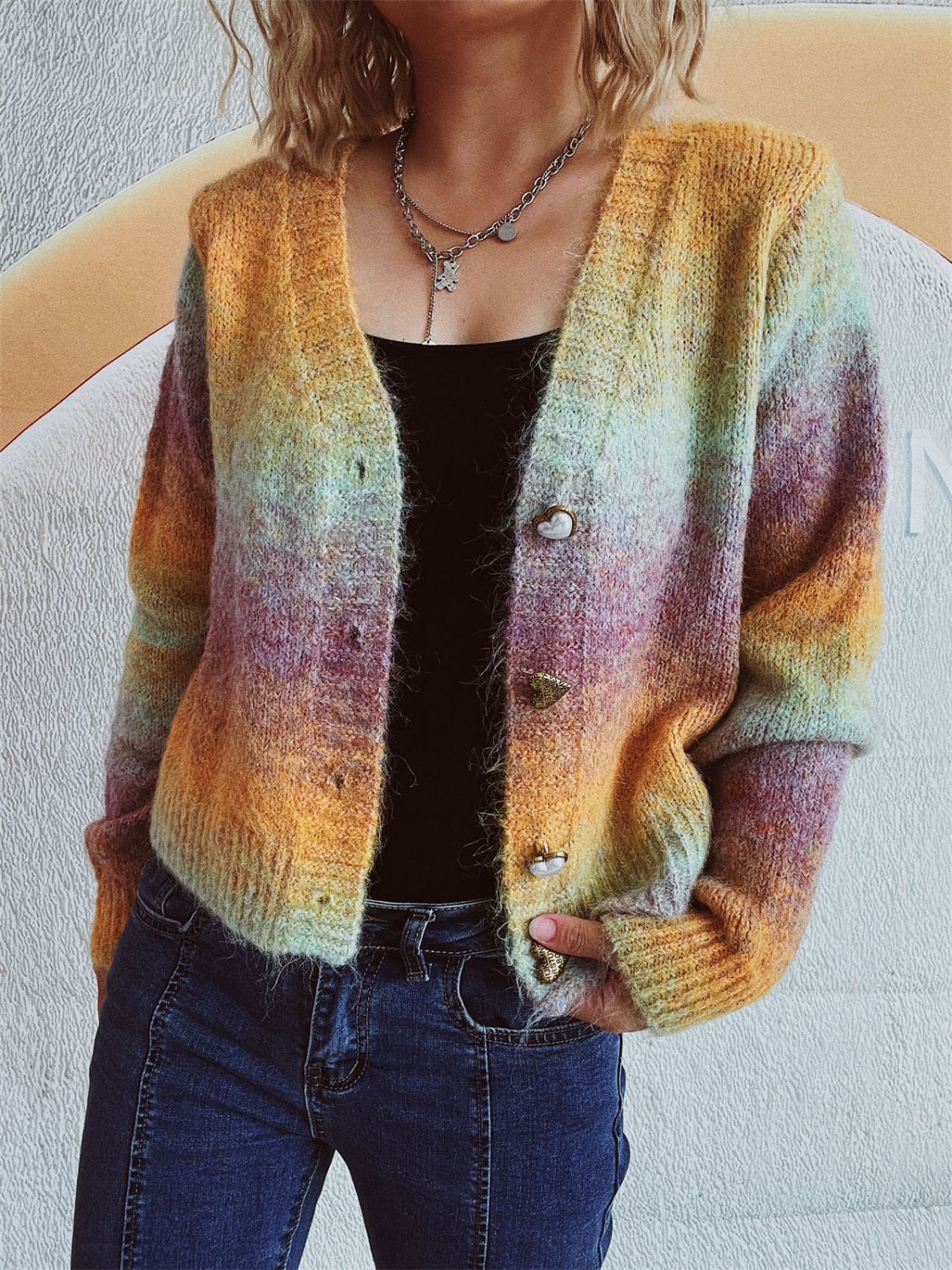 Ombre knit cardigan with heart buttons and a V-neck, featuring multicolor hues of orange, yellow, and purple.