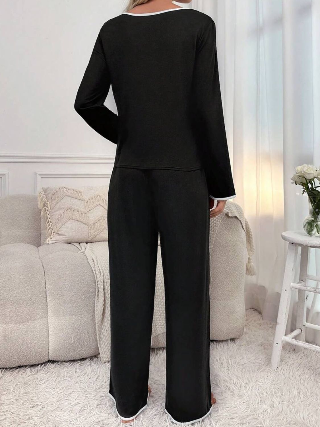 Black lounge set with contrast trim on neckline and cuffs, long sleeves, and wide-leg pants.