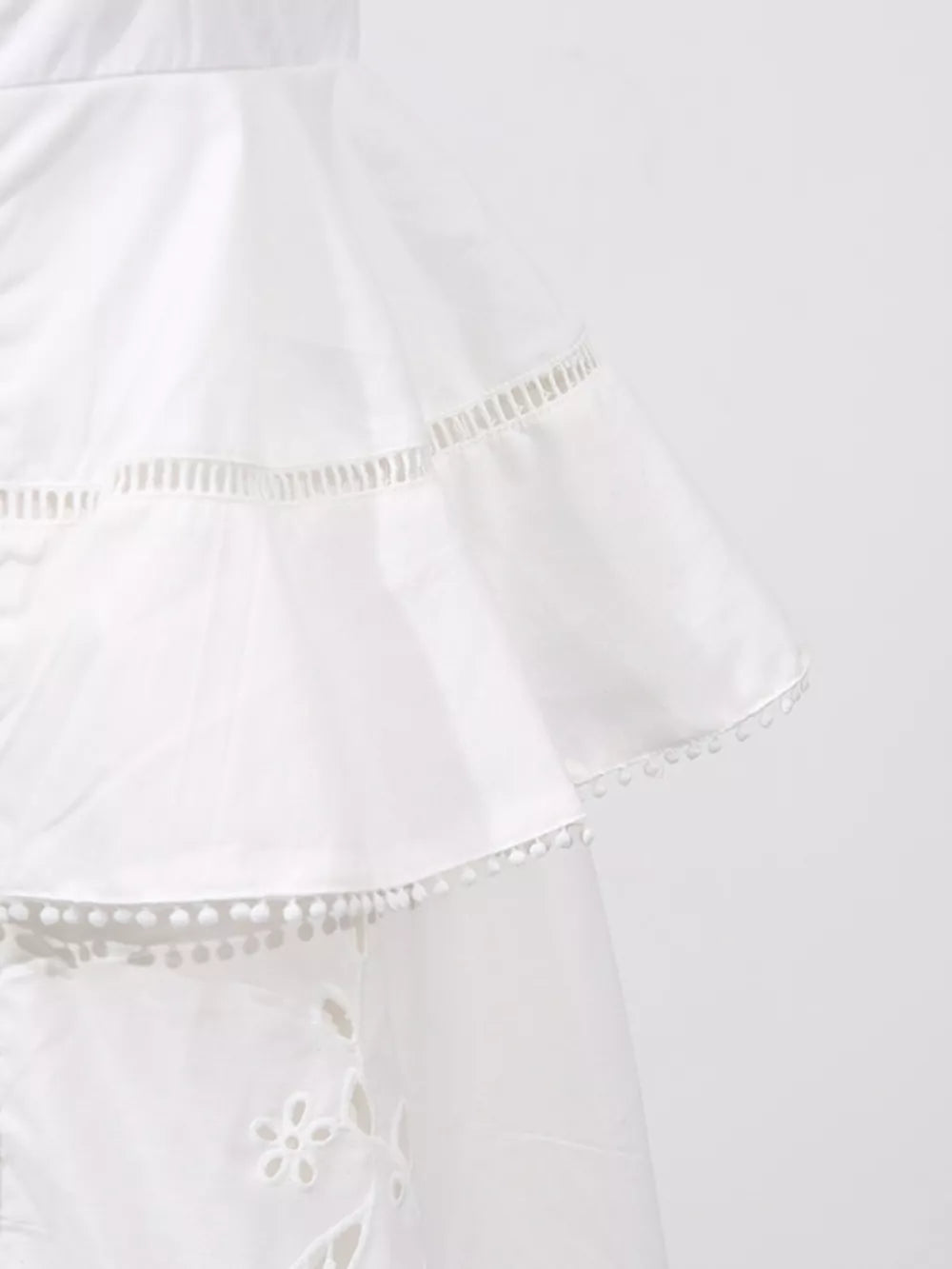 White eyelet embroidered midi dress with tiered ruffles and pom-pom trim.
