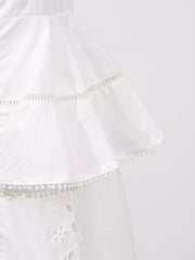 White eyelet embroidered midi dress with tiered ruffles and pom-pom trim.