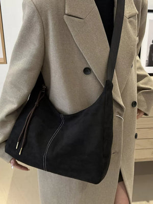 Black suede crossbody bag with adjustable strap and contrast stitching