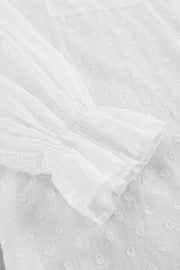 White textured ruffle trim shirt with gathered sleeves and a dotted pattern.
