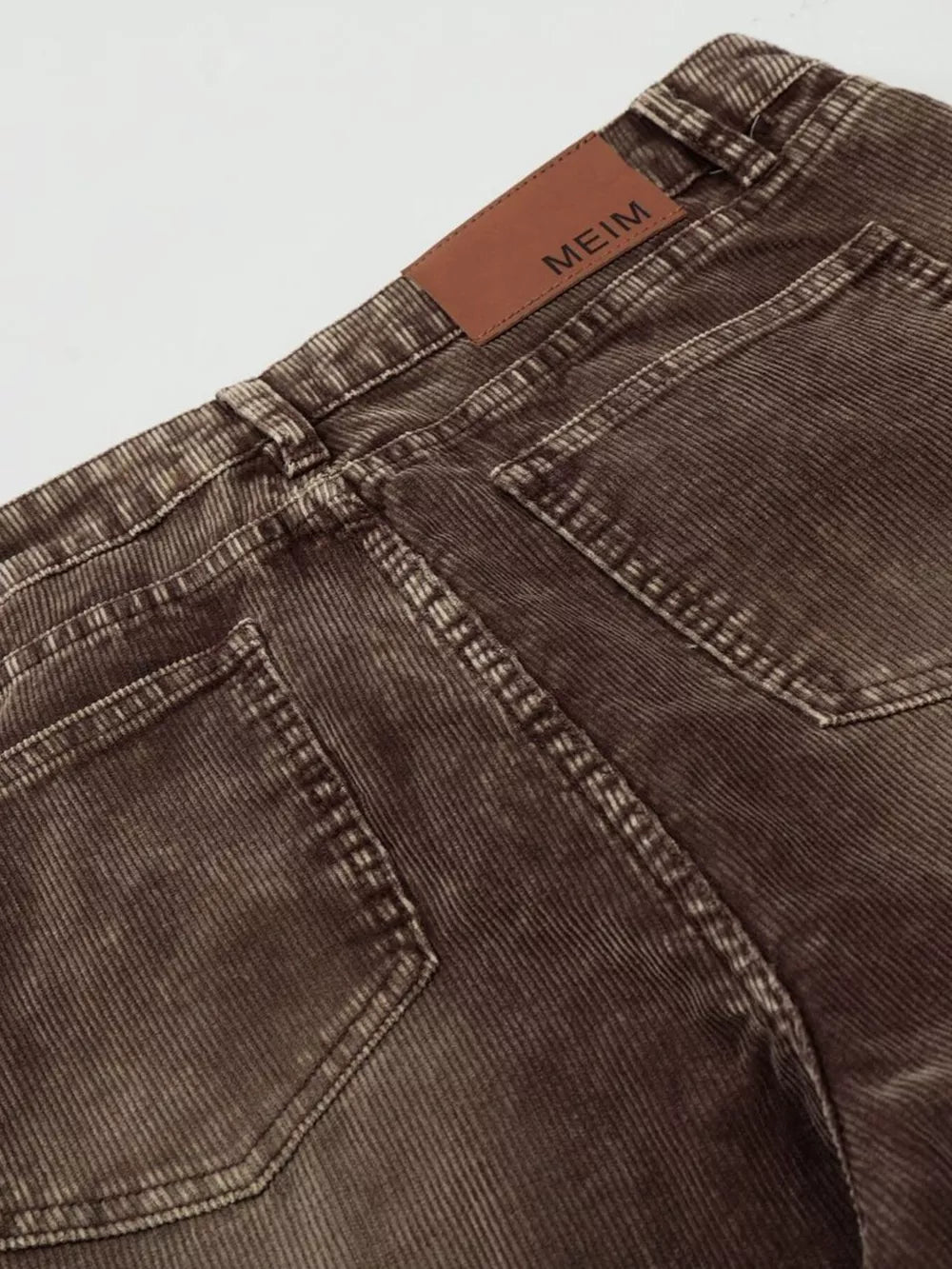 Brown corduroy joggers for men, showing back pockets and leather logo patch.