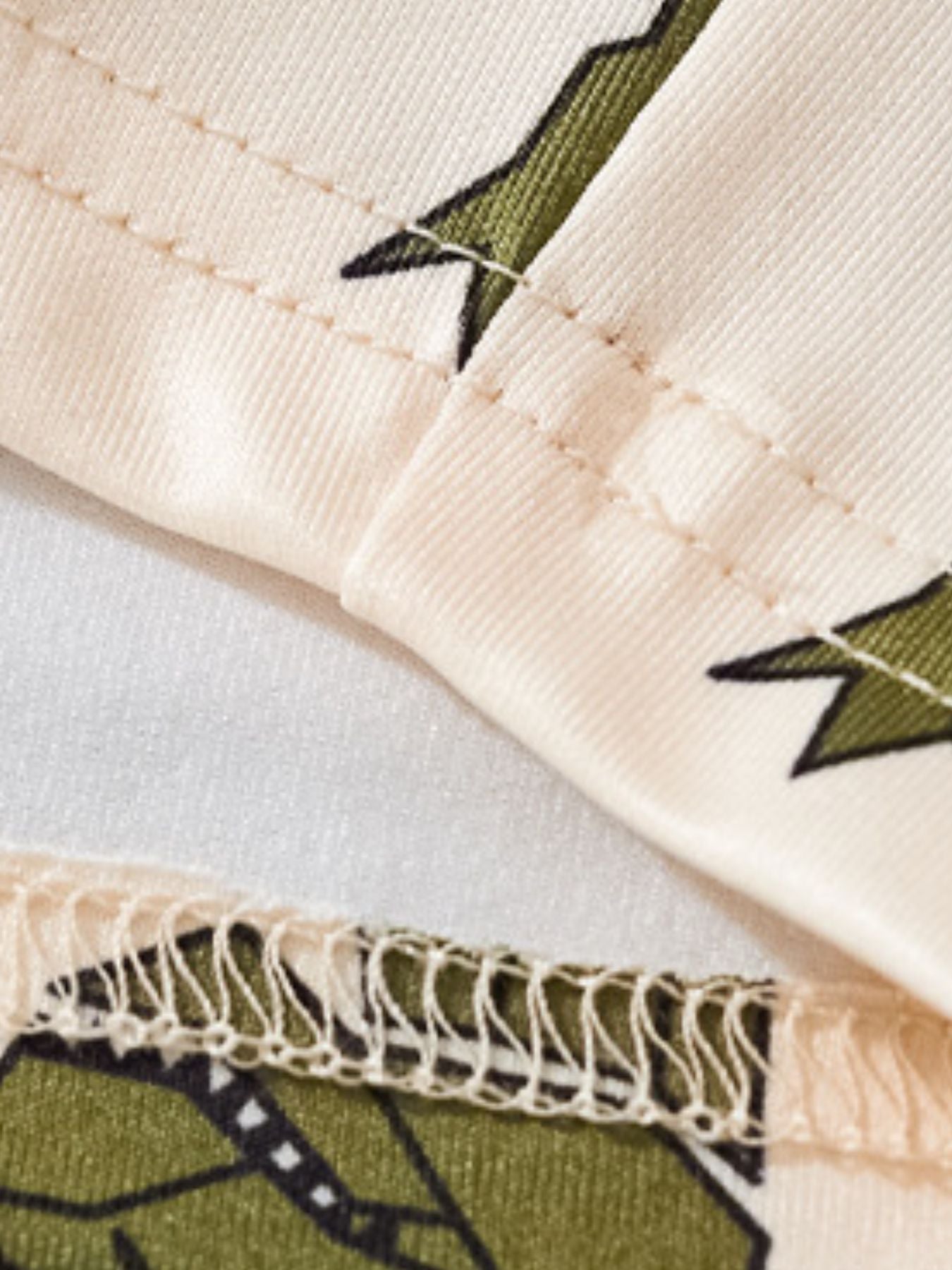 Toddler dinosaur print tee and shorts set in cream with green dinosaur pattern and stitched details.