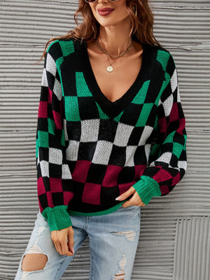 Geometric checkerboard V-neck knit sweater with puff sleeves in black, green, white, and maroon.