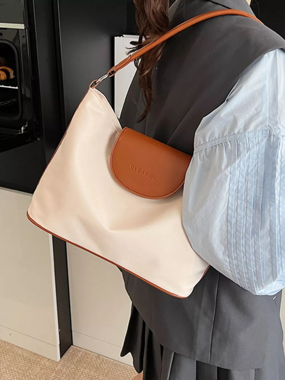 Chic canvas hobo crossbody bag in ivory with brown trim and a tan flap pocket.