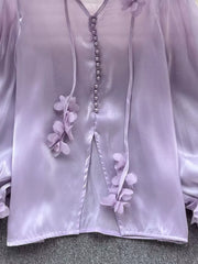 Purple sheer button-down shirt with delicate floral appliqué and bow details.