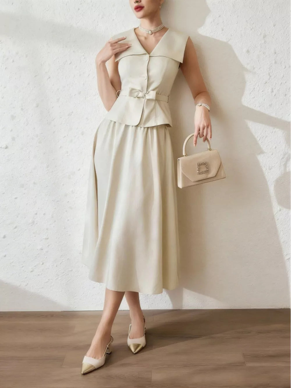 V-neck peplum top and midi skirt set in cream with a bow belt and button details.