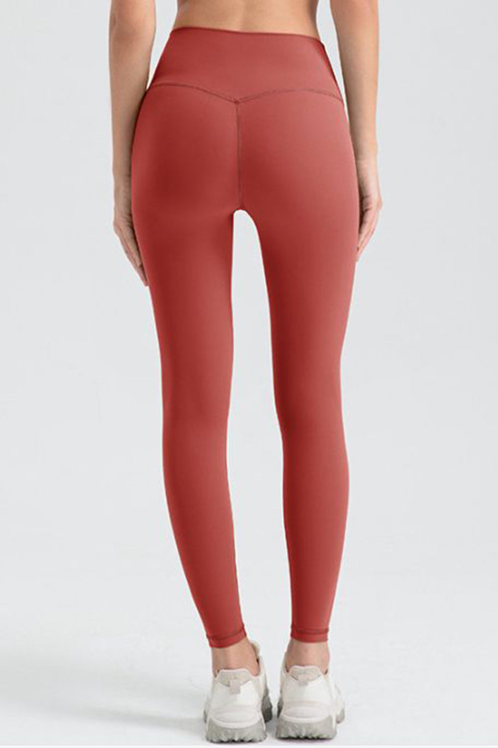 Women's red orange sculpted contour leggings with V-seam detail.