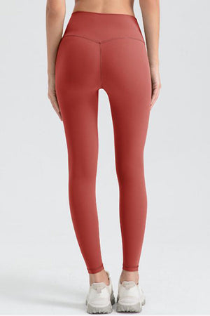 Women's red orange sculpted contour leggings with V-seam detail.