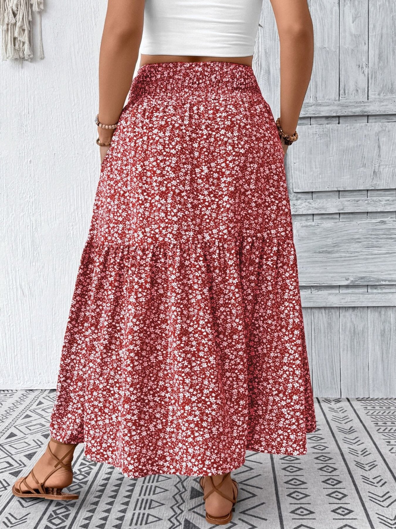 Tiered maxi skirt in red with a white floral print, featuring a smocked waist and airy, casual style.