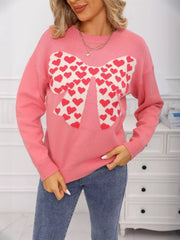 Pink acrylic knit sweater with round neck and large bow pattern filled with red hearts.