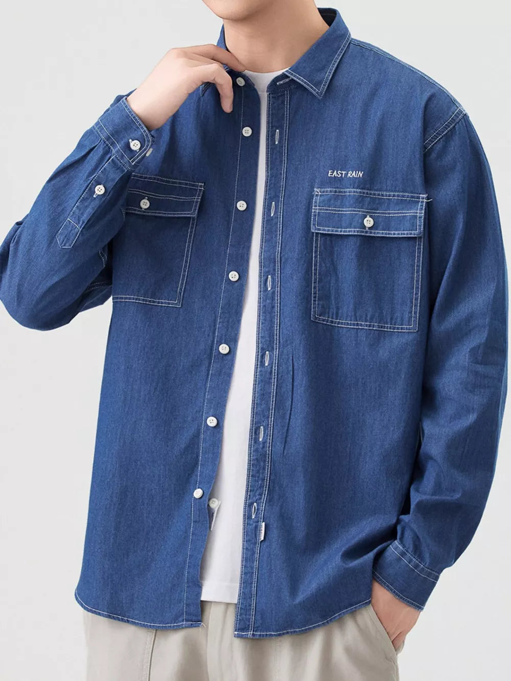 Blue denim button-up shirt with chest pockets and white contrast stitching.