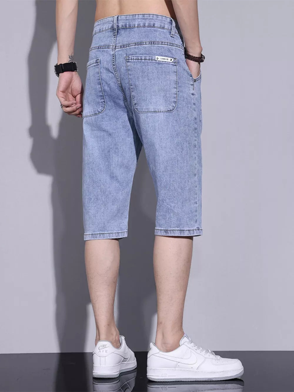 Light blue washed denim shorts for men with button closure and back pockets.