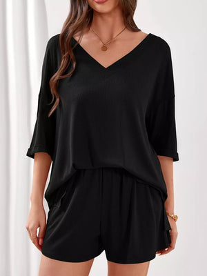 Black V-neck two-piece loungewear set with cuffed sleeves and elastic waist shorts.